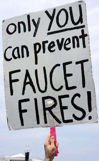 Someone holding up a sign that says Only You can Prevent Faucet Fires!