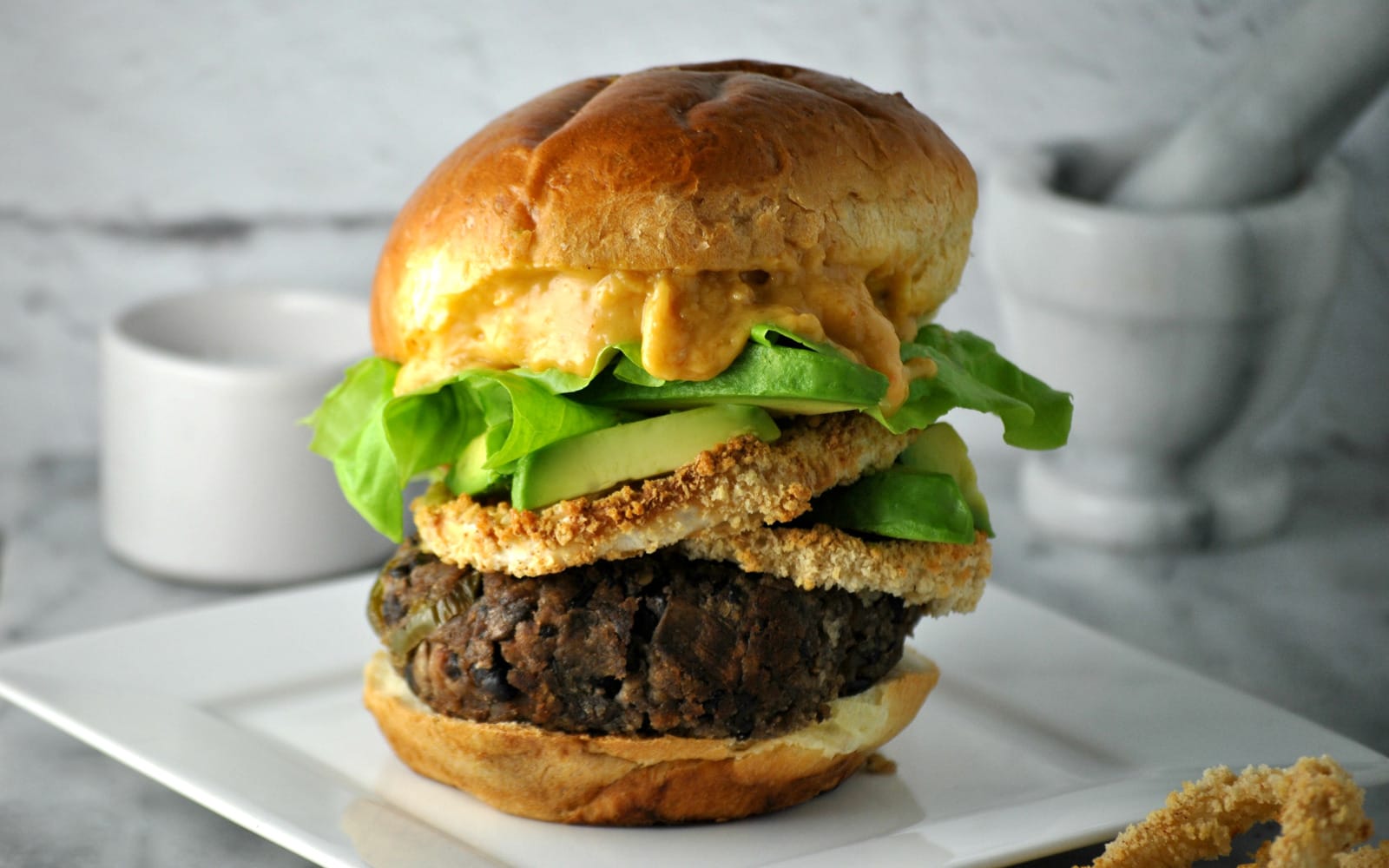 Homemade black bean burger with beer cheese and onion rings