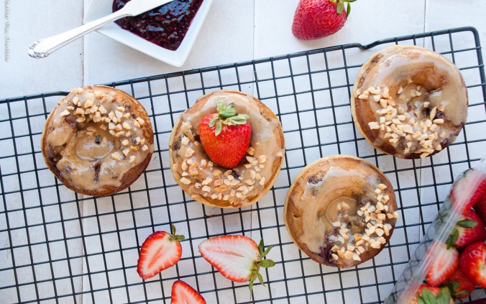 Vegan Healthier Peanut Butter and Jelly Baked Doughnuts with glaze, strawberries, and nuts to top