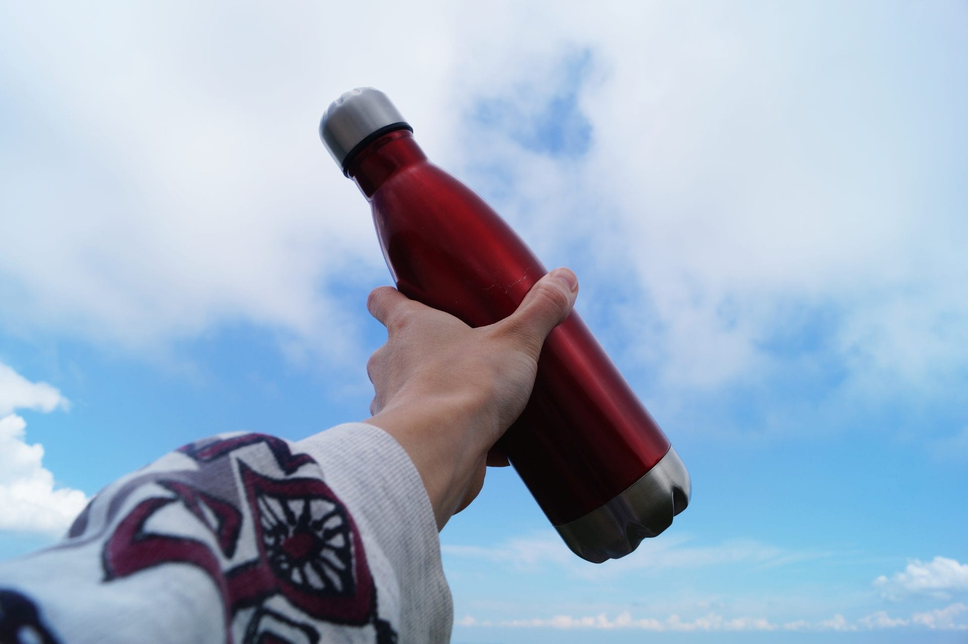 hand holding red stainless steel reusable water bottle