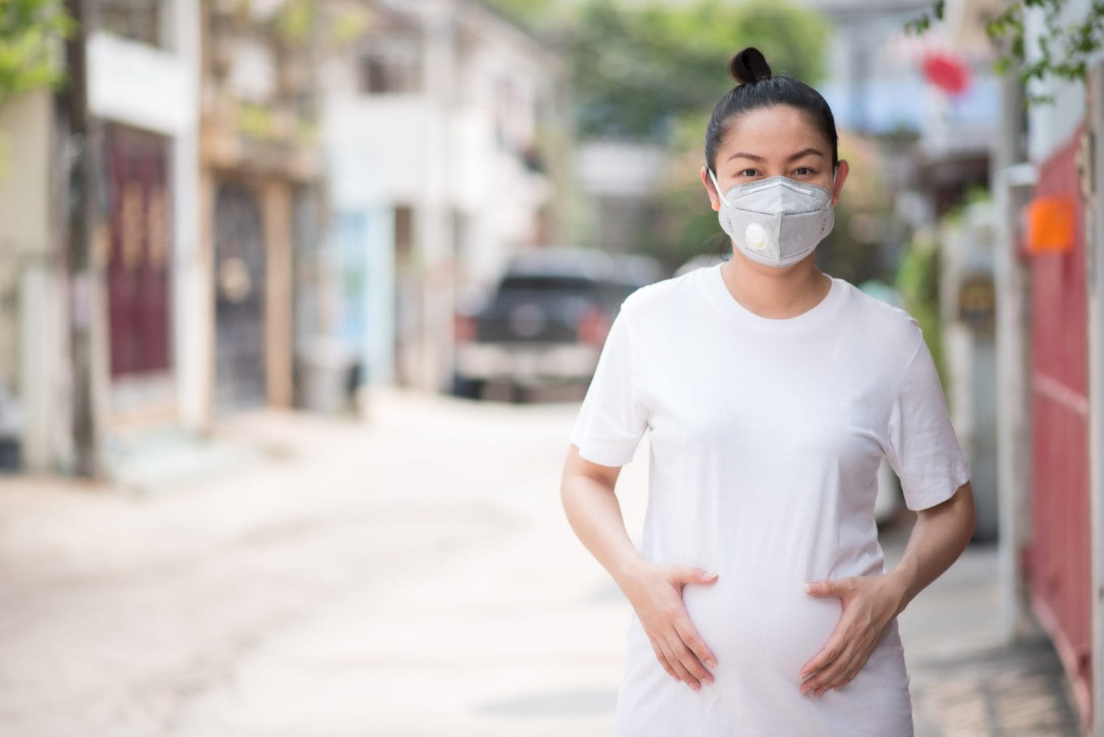 Pregnant woman holding belly with a mask on