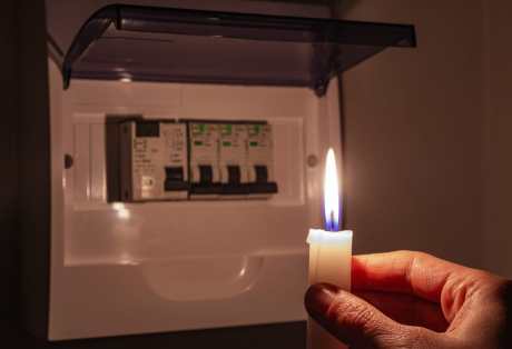 holding a candle to investigate a home fuse box